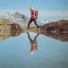 Hiker in full outdoor gear crossing a mountain stream