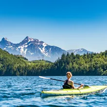 Woman kayaking on a mountain lake surrounded by forest