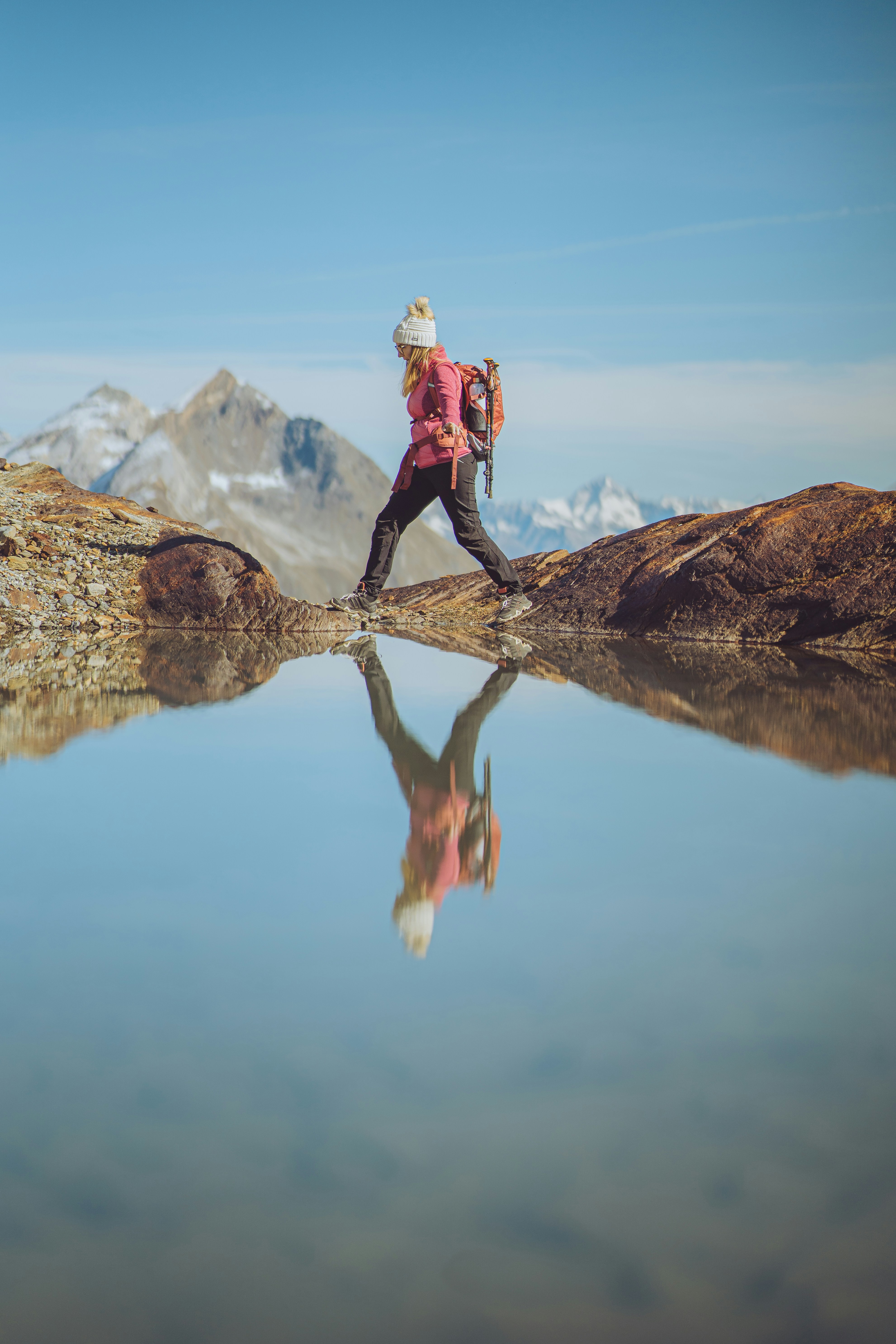Hiker in full outdoor gear crossing a mountain stream