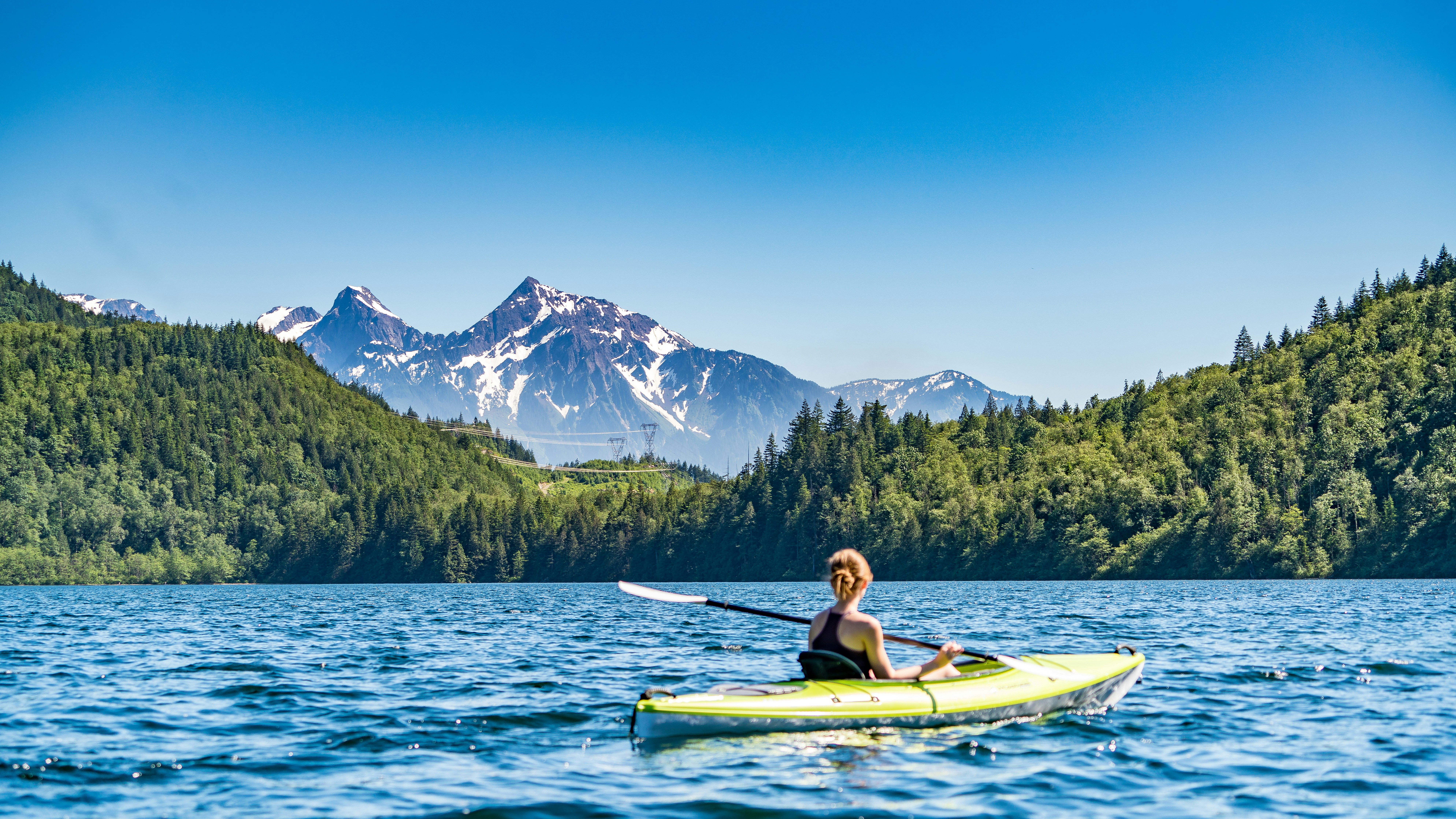 Woman kayaking on a mountain lake surrounded by forest